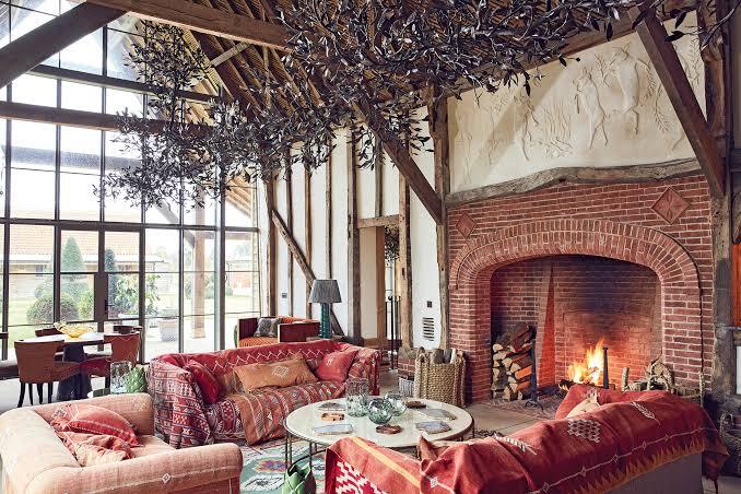 Timber-framed barn lounge with a roaring brick fireplace and deep sofas