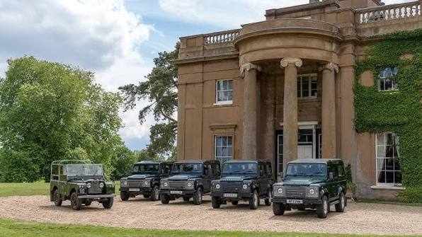 Land Rover Defenders lined up outside the estate's manor house