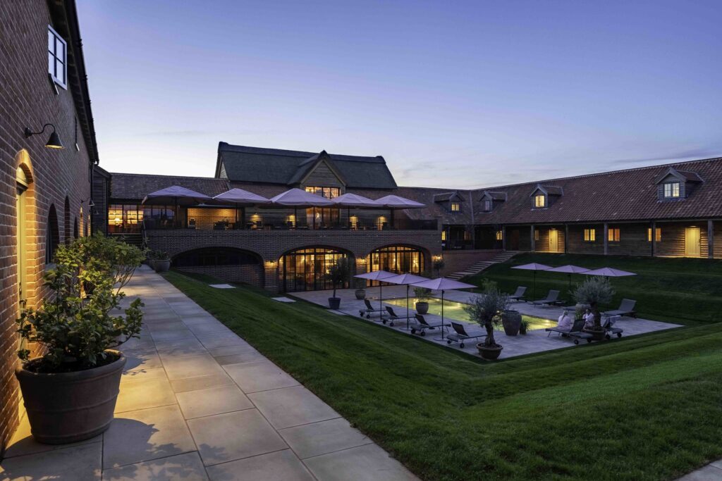Estate courtyard and pool at dusk with parasols and warm window light